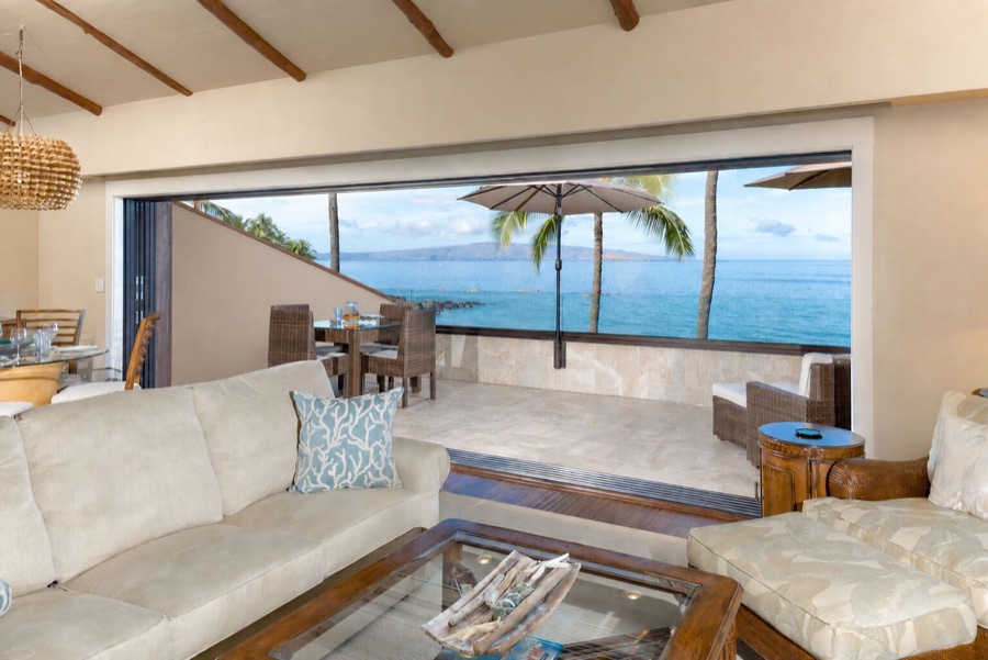 The living room with the sliders open to the lanai and the ocean